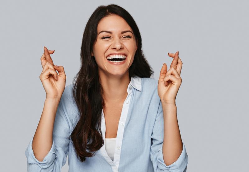 A woman with her fingers crossed finding 8 ways to get luckier when searching for a job interview