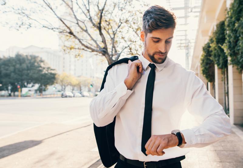A man looking at his watch wondering "Can I be too early to a job interview?"