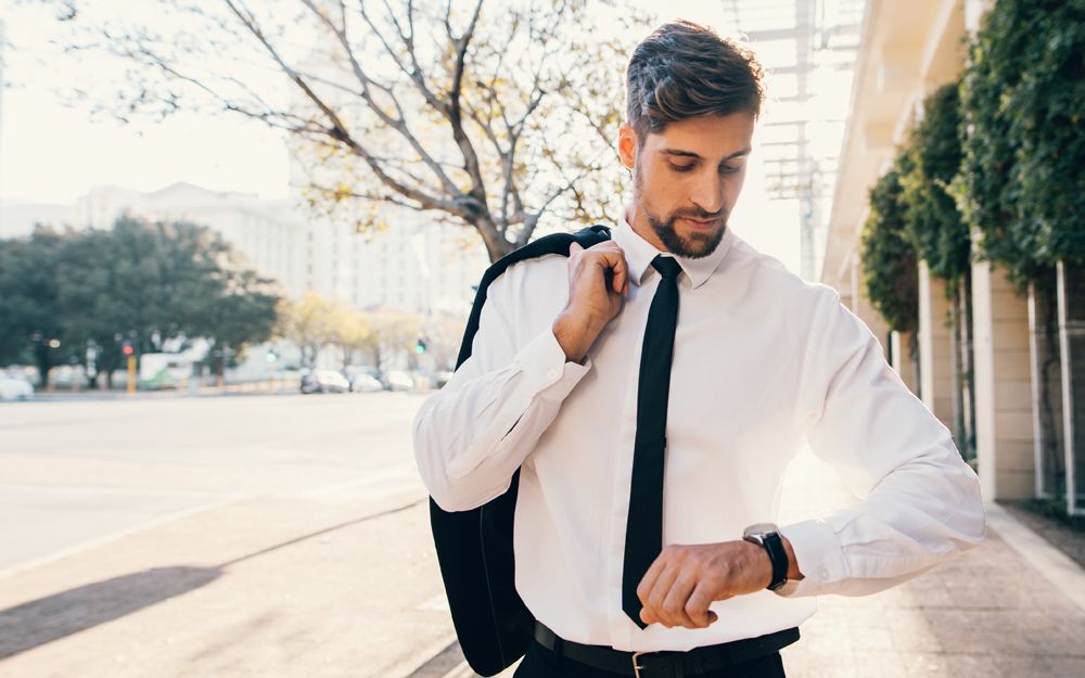 A man looking at his watch wondering "Can I be too early to a job interview?"