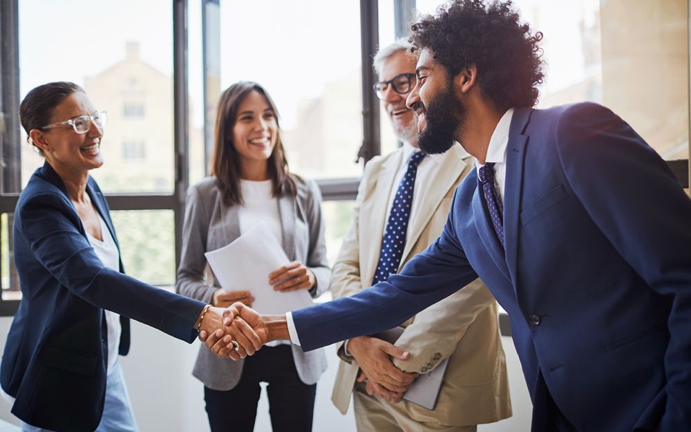 A candidate dressed appropriately for a job interview shaking hands with a recruiter