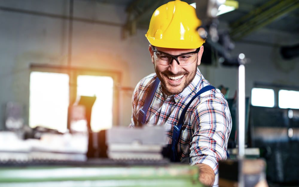 A manufacturing plant manager happy because his warehouse is thriving with new recruits thanks to TalentWorld, a recruitment agency. 